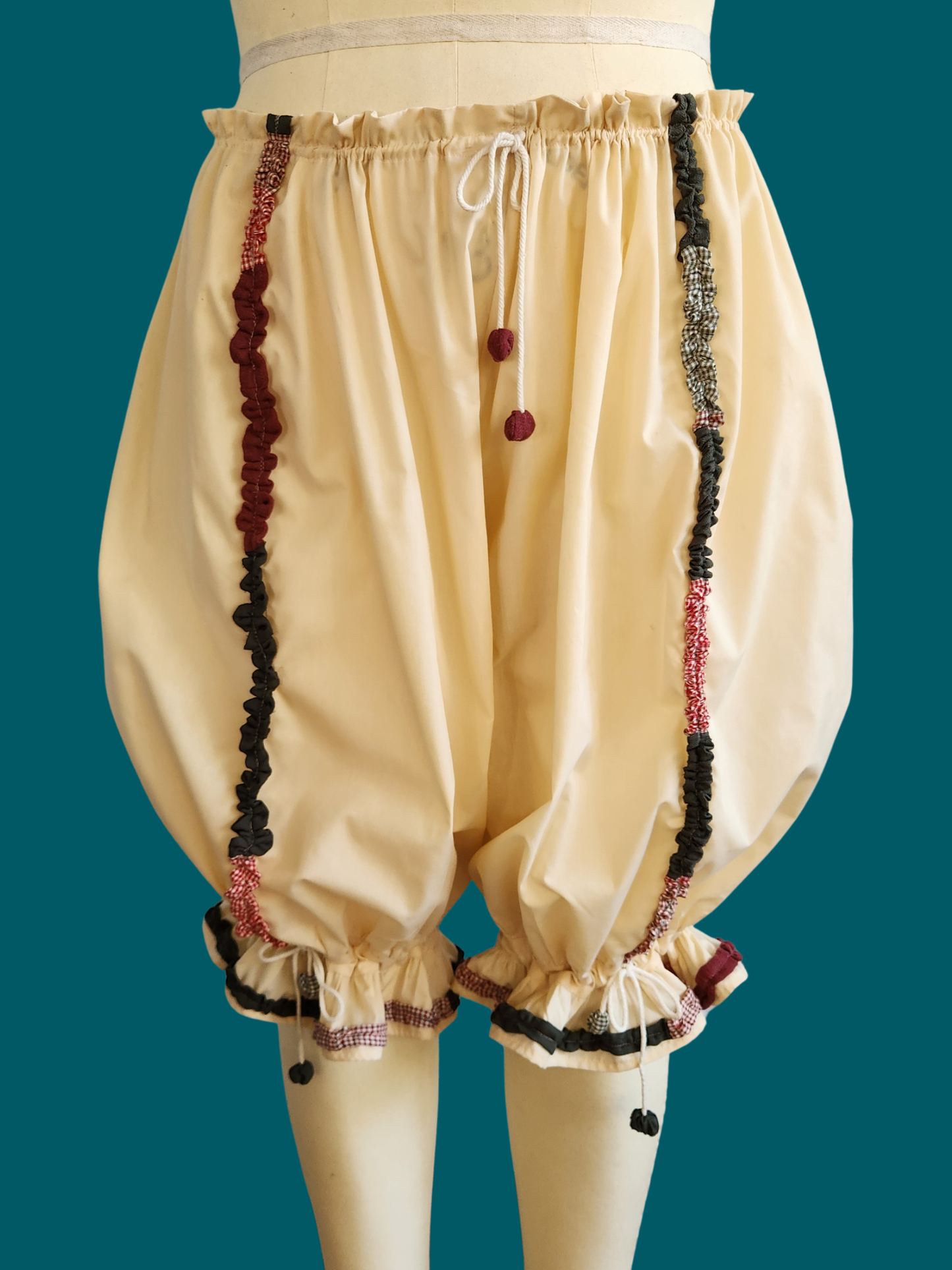 Beige bloomers with decorative trim on a teal background