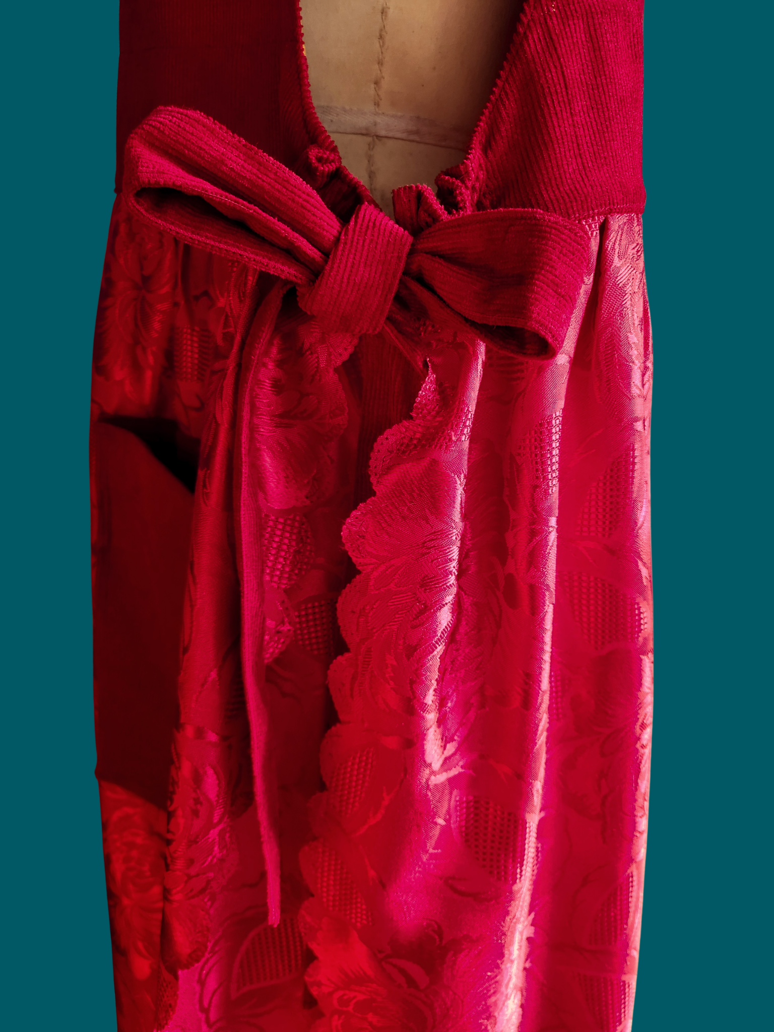 Red lace dress with a large bow on a teal background
