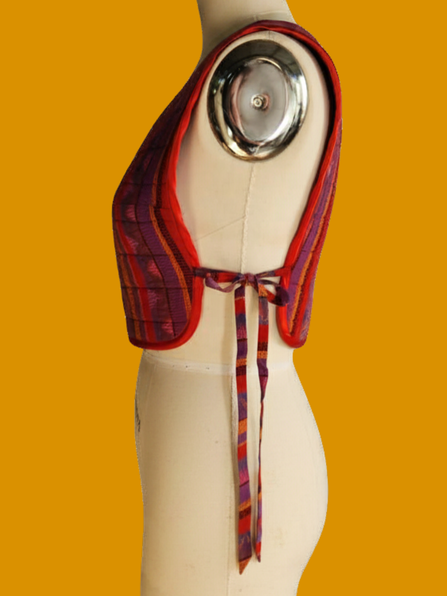 Mannequin wearing a colorful scarf with a metallic object on an orange background