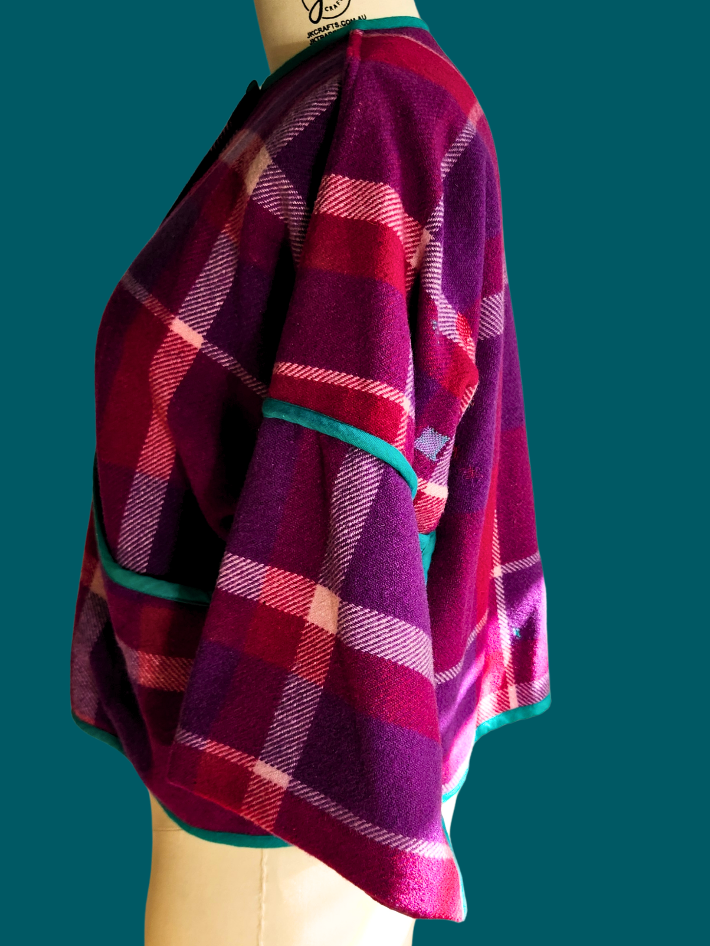 left side of pink plaid jacket on size 18 model on teal background