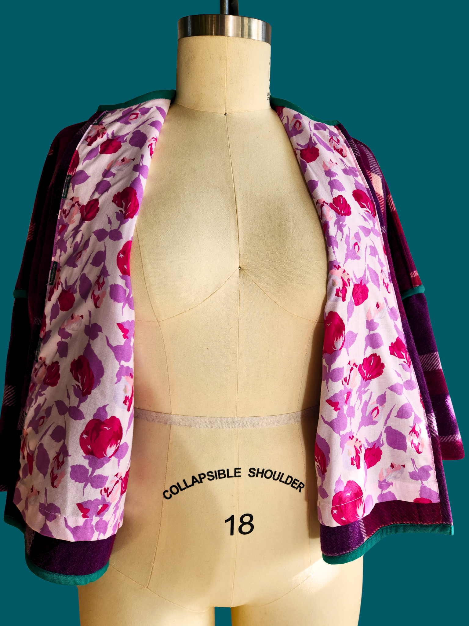 pink, purple and white floral lining of pink plaid jacket on size 18 model on teal background