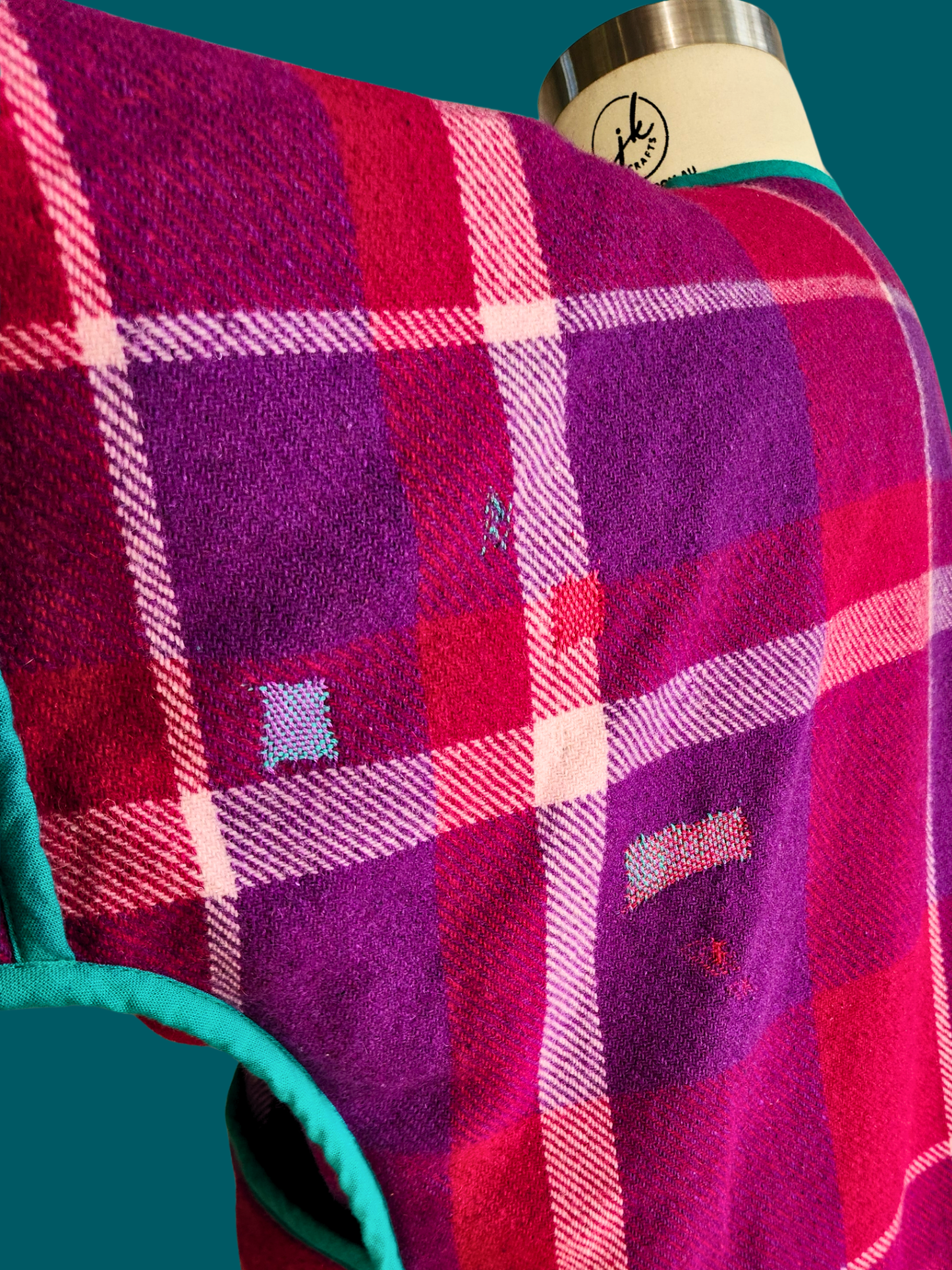 visible mending on pink plaid jacket back on teal background