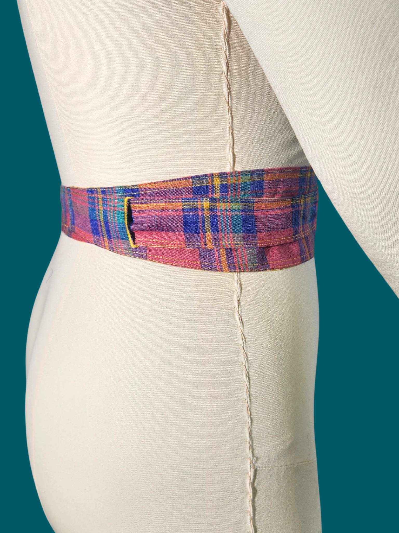 Mannequin wearing a plaid belt with a teal background