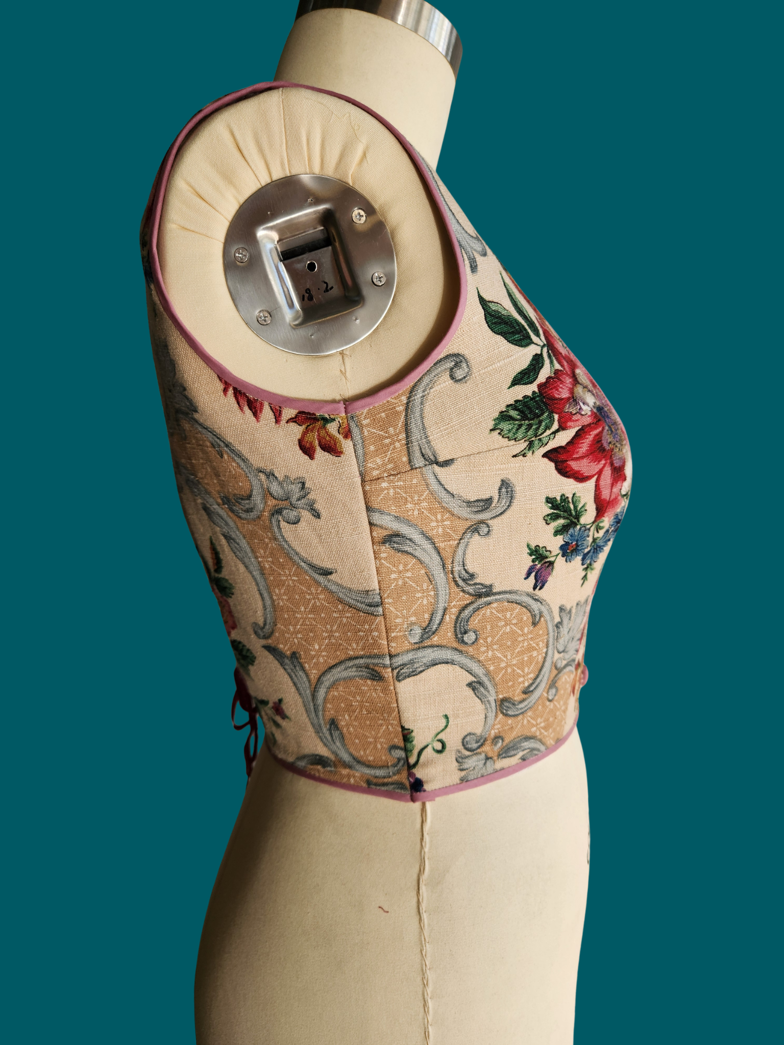 Decorative vest on a mannequin against a teal background