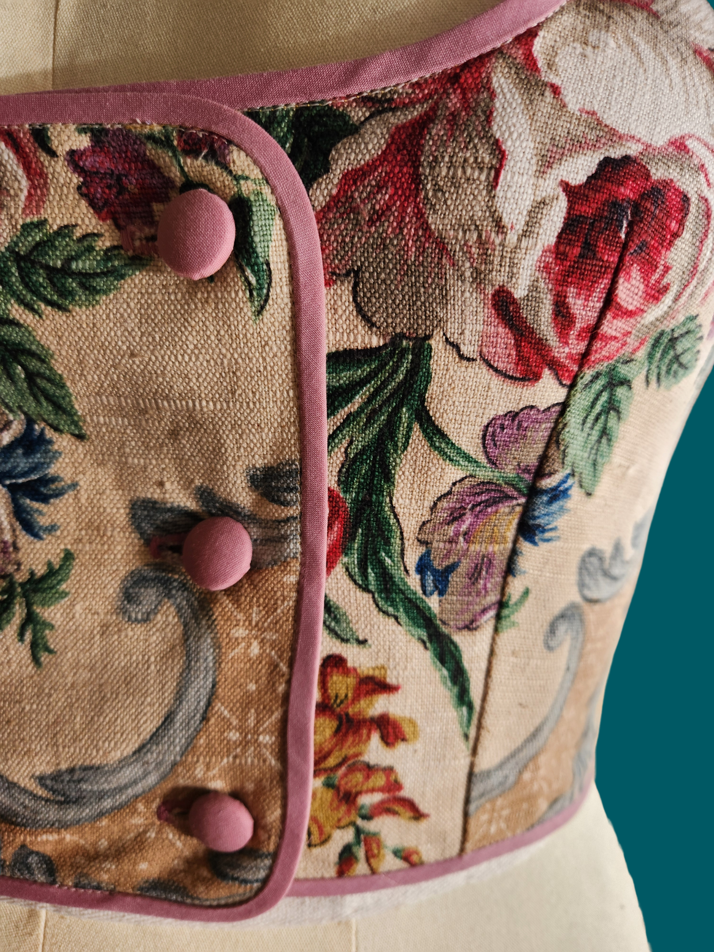 Floral patterned fabric with pink buttons on a mannequin against a teal background