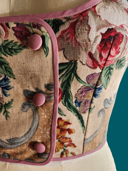 Floral patterned fabric with pink buttons on a mannequin against a teal background