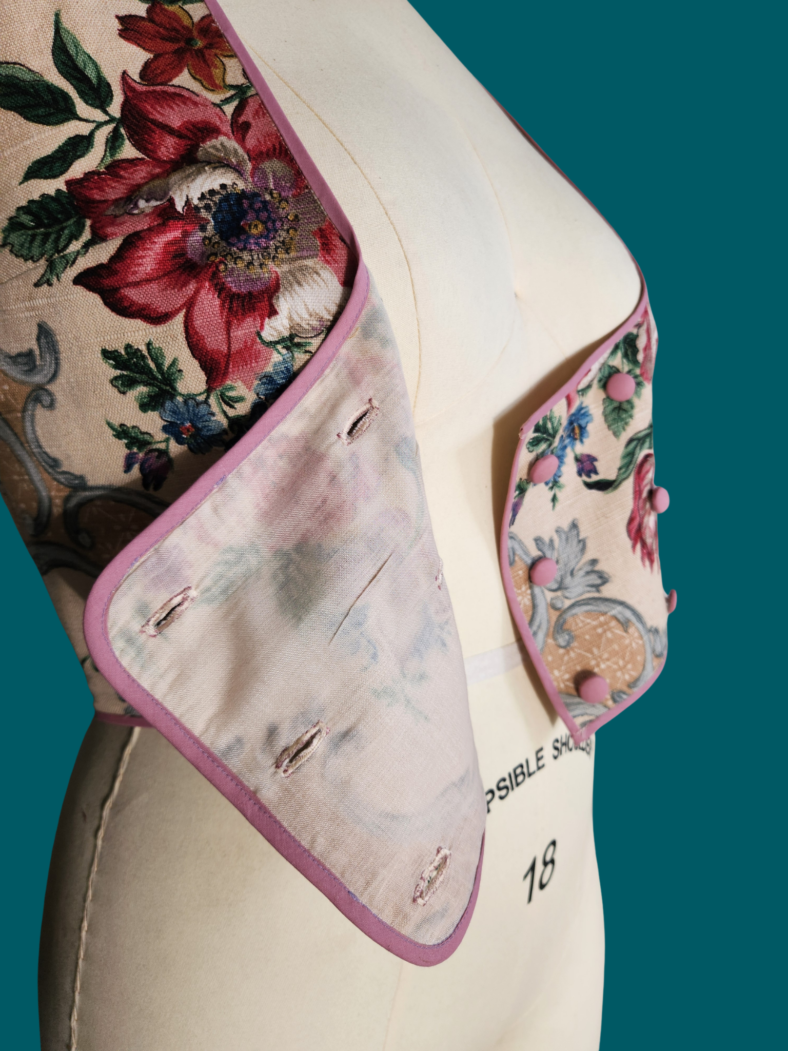 Floral-patterned shawl draped over a mannequin with 'Collapsible Shoulder' label on a teal background