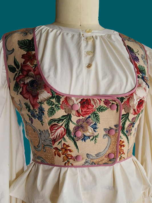 Floral embroidered vest on a mannequin against a teal background