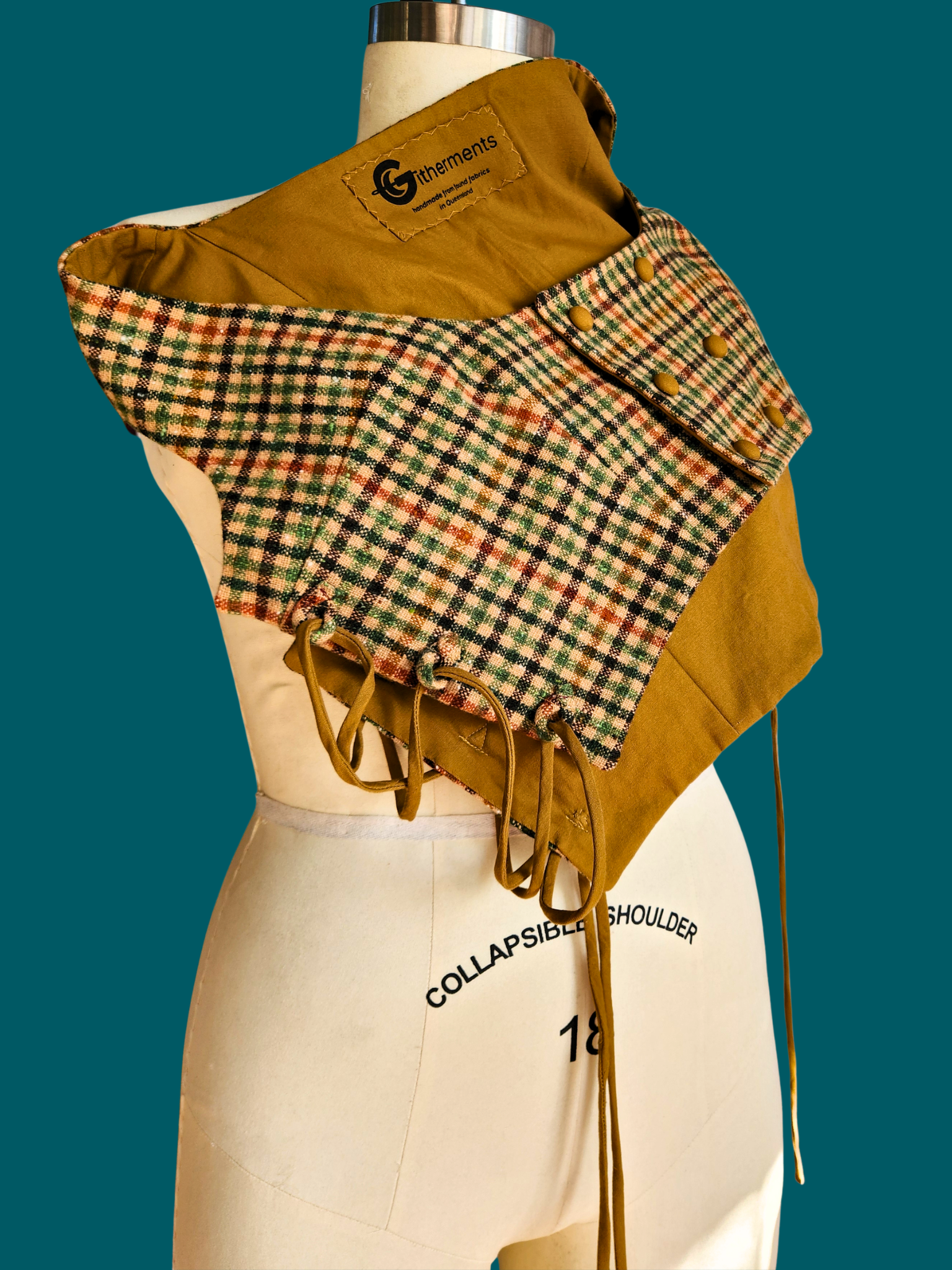 Mannequin wearing a mustard yellow jacket with a plaid collar against a teal background