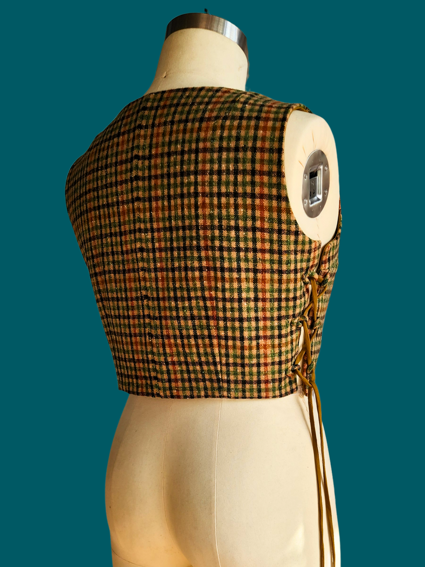 Plaid vest on a mannequin against a teal background