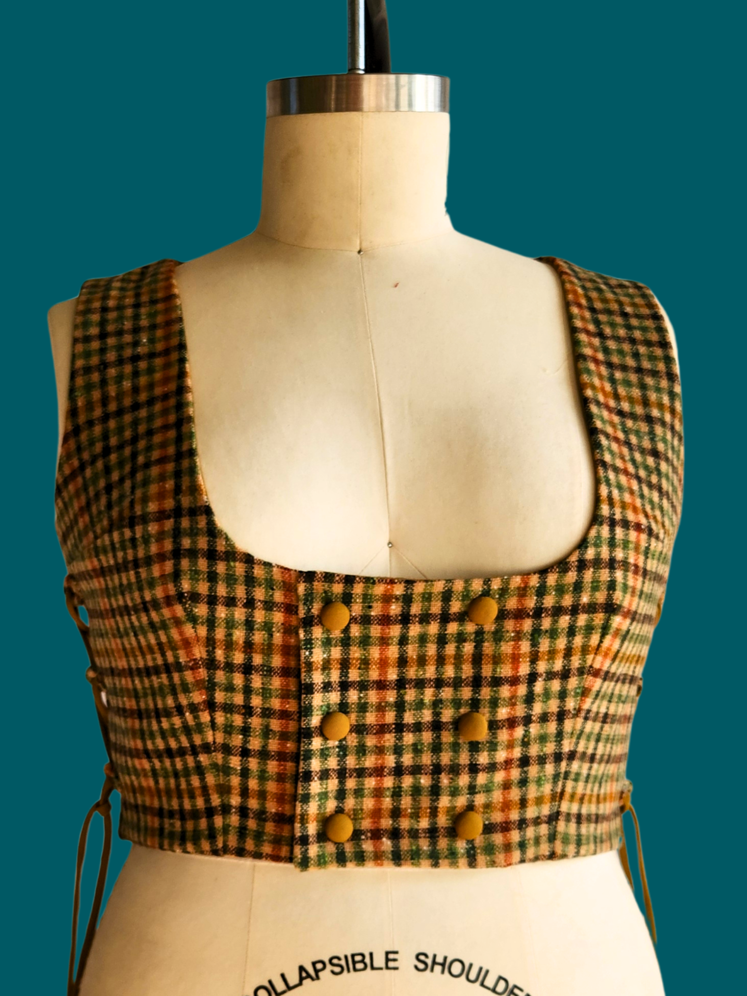 Plaid vest on a mannequin with a teal background