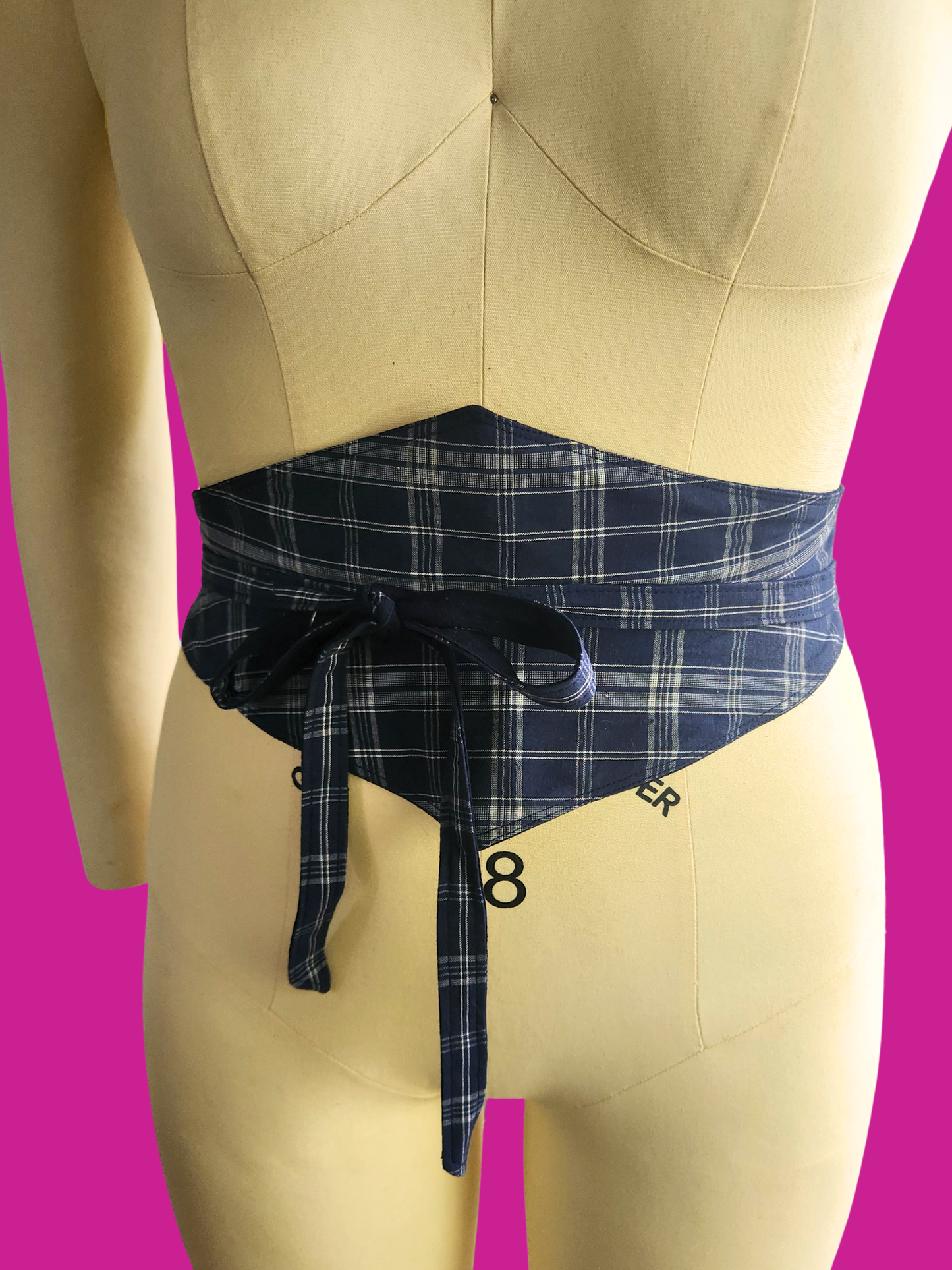 Mannequin wearing a navy plaid apron against a pink background