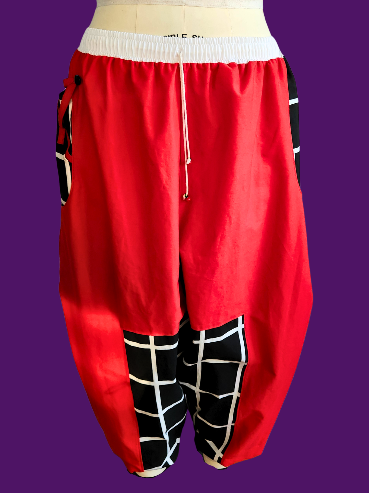Red baggy pants with black and white checkered patterns on a purple background