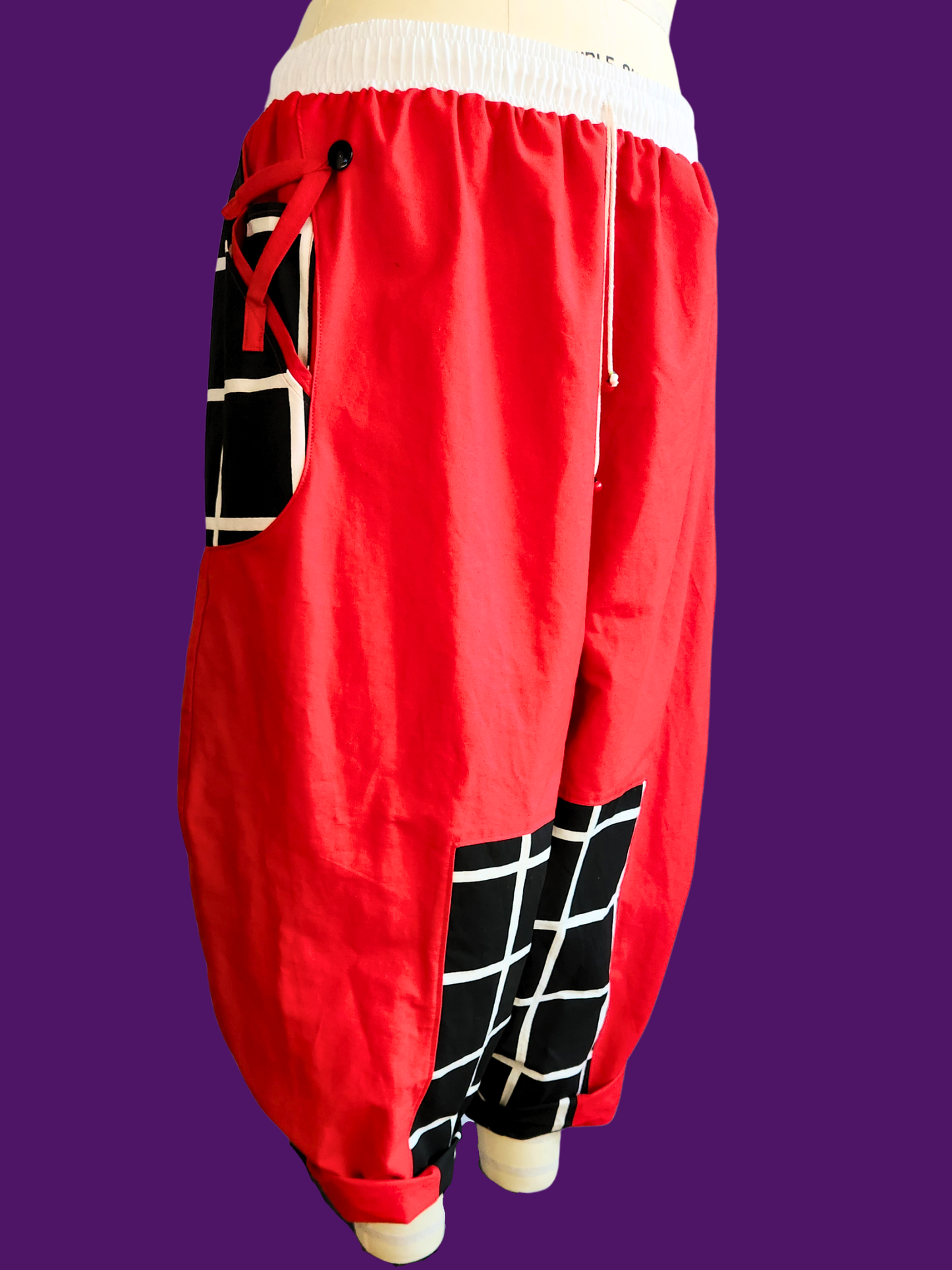 Red baggy pants with black and white pattern on a purple background
