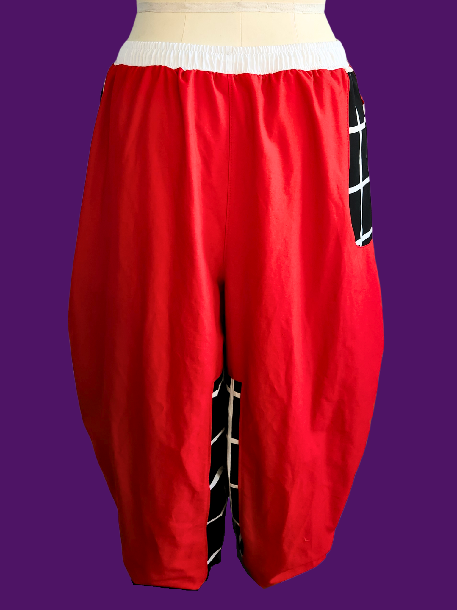 Red baggy pants with a white waistband on a purple background