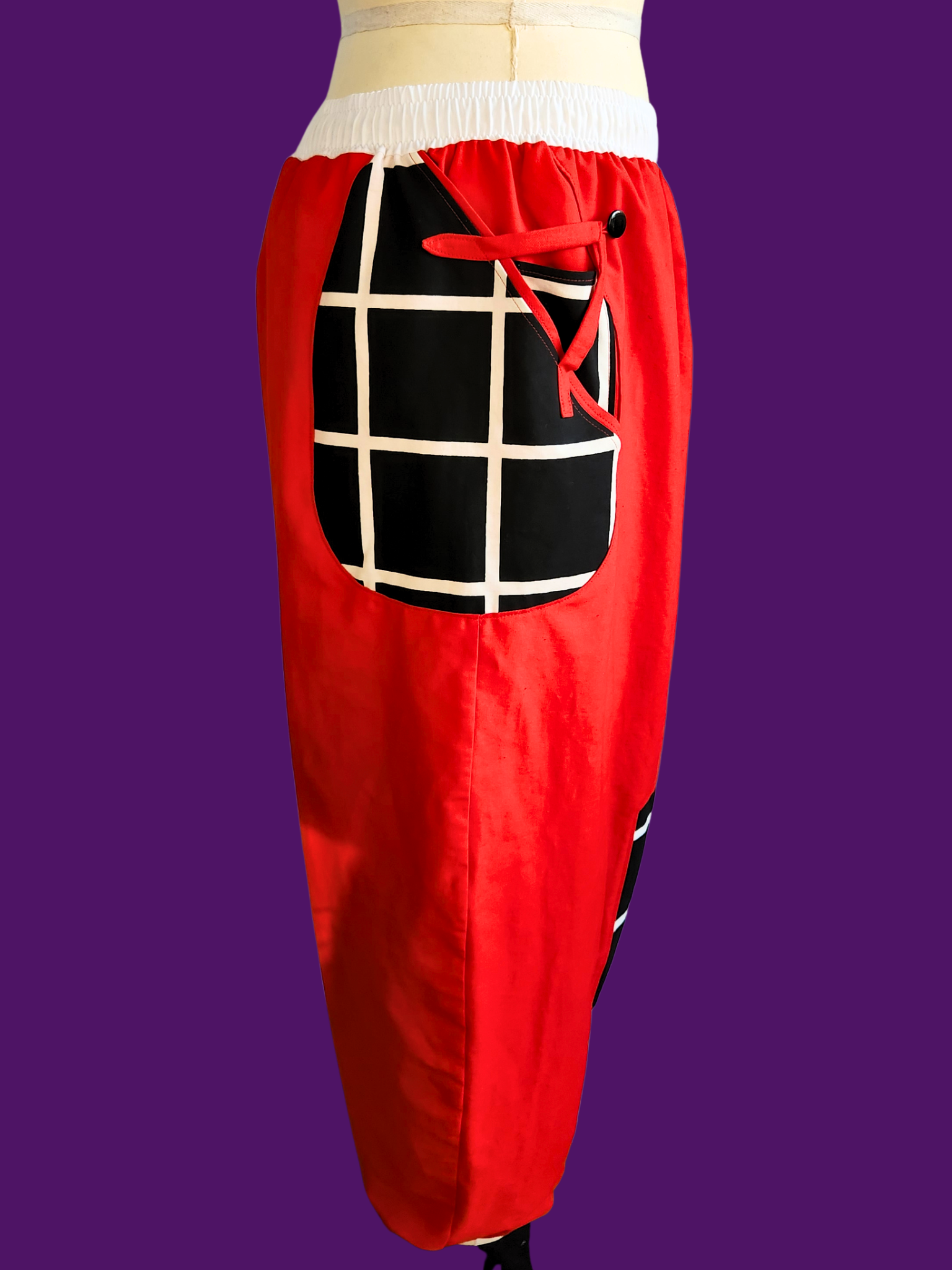 Red pants with a black and white checkered pocket on a purple background