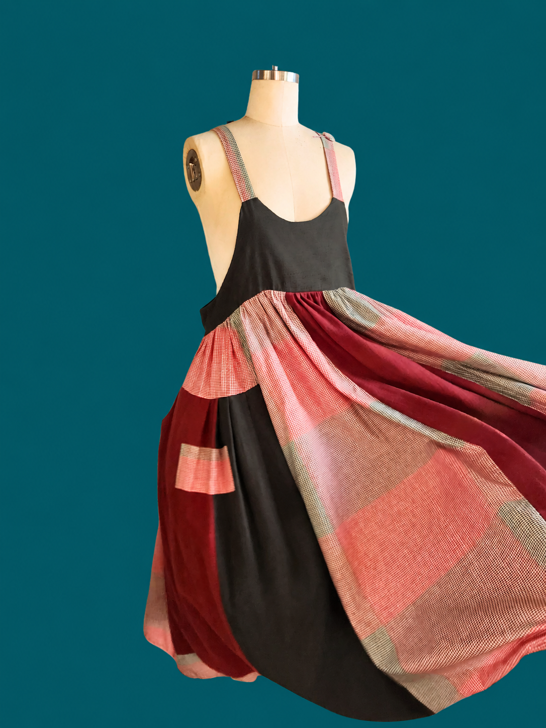 Mannequin wearing a dress with a colorful plaid pattern on a teal background