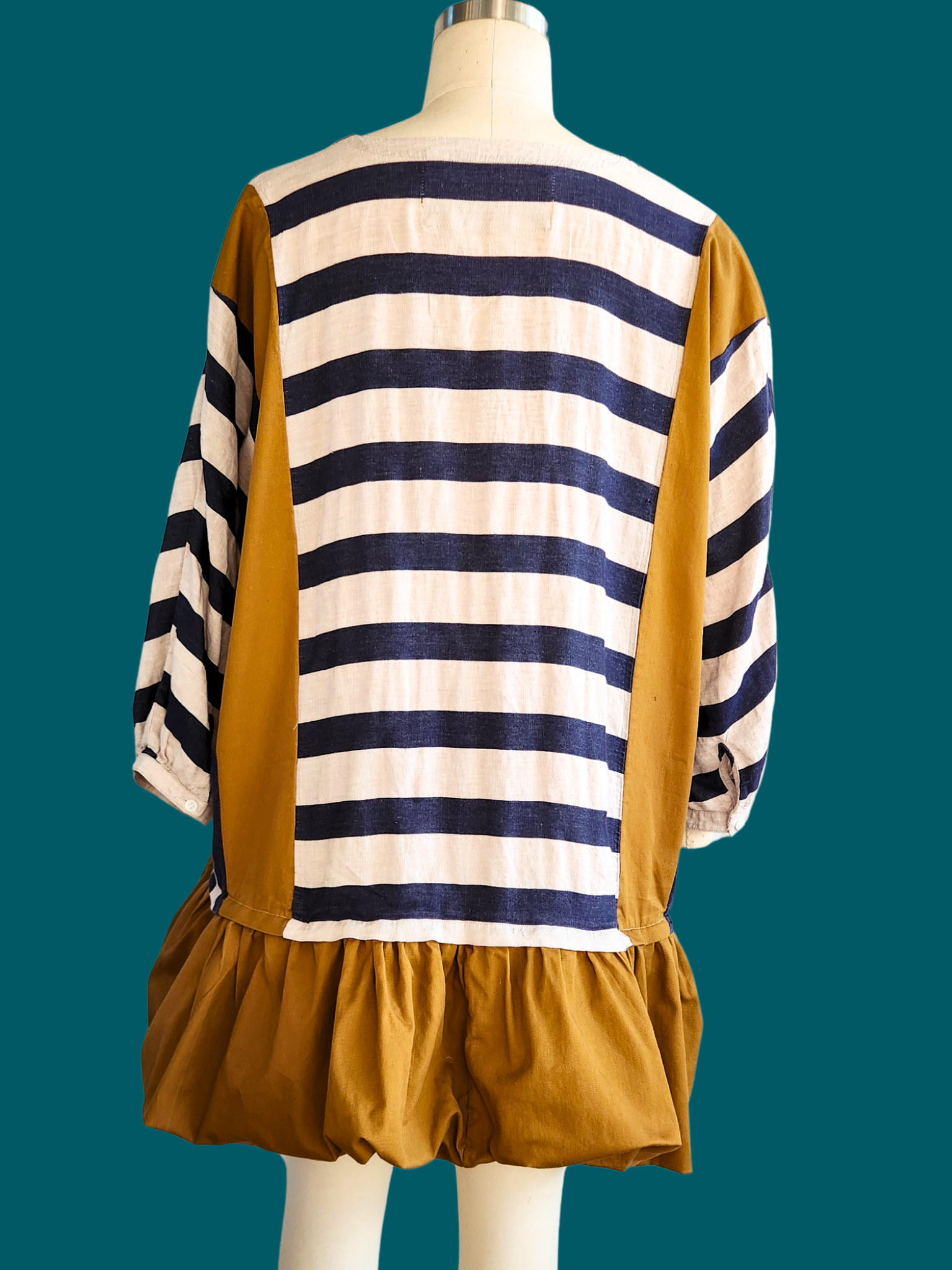 Mannequin wearing a dress with a striped pattern on a teal background