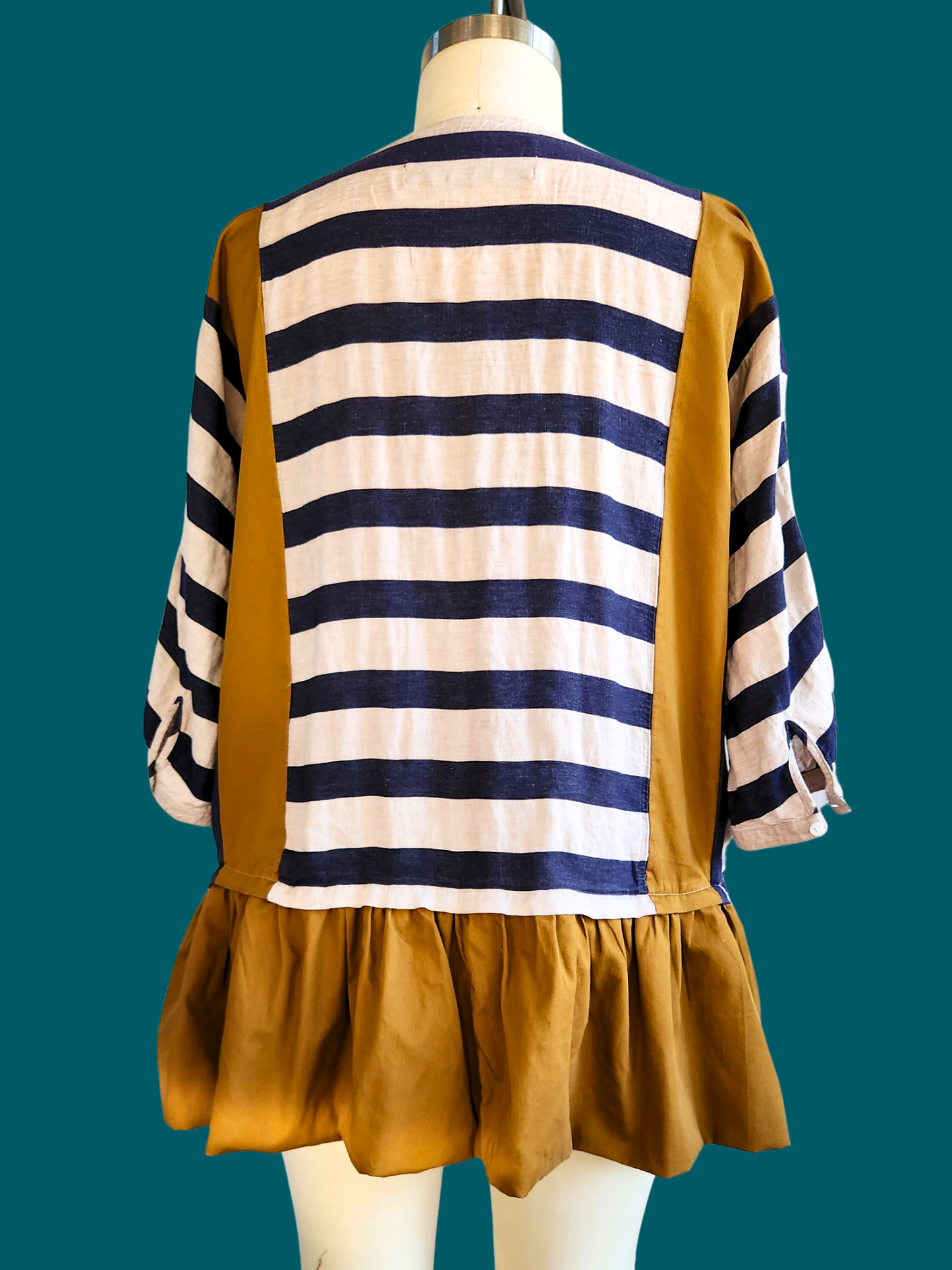 Mannequin wearing a striped shirt with mustard yellow accents on a teal background