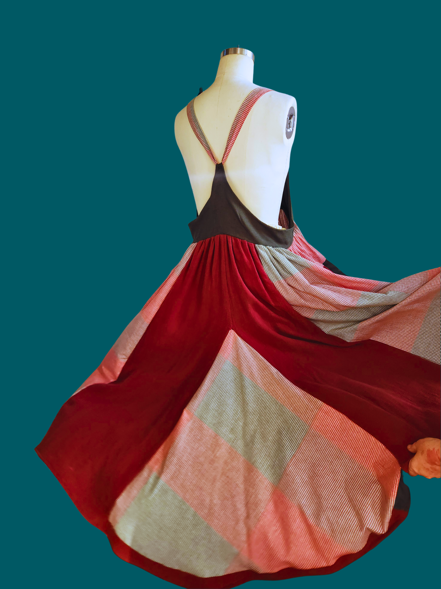 Mannequin wearing a colorful dress with a red and pink pattern on a teal background